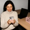 A smiling woman focused on her smartphone at work.