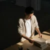 A man standing at a desk, arranging papers in front of him